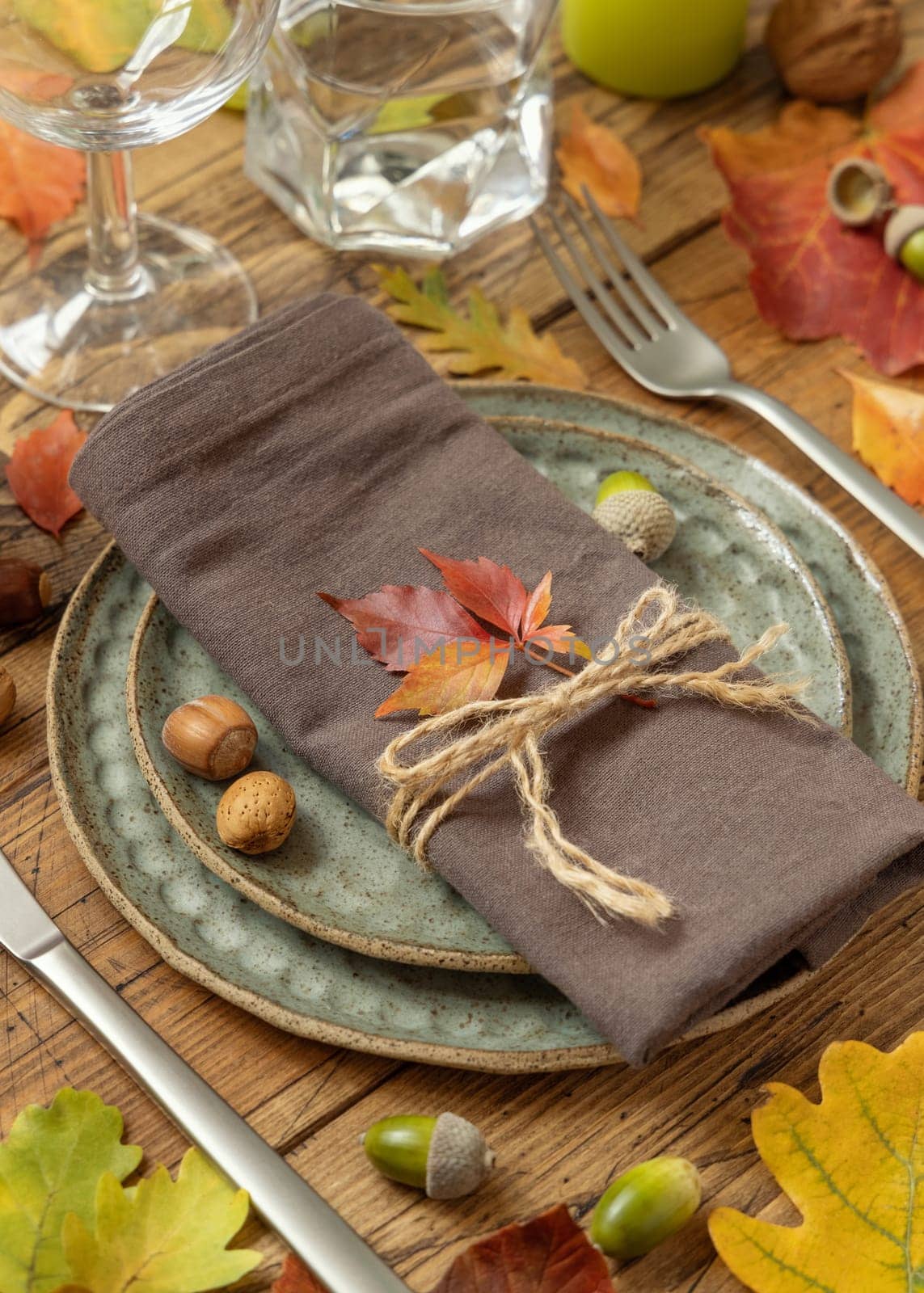 Autumn rustic table setting between leaves and berries on vintage wooden table close up. Thanksgiving, halloween or harvest concept