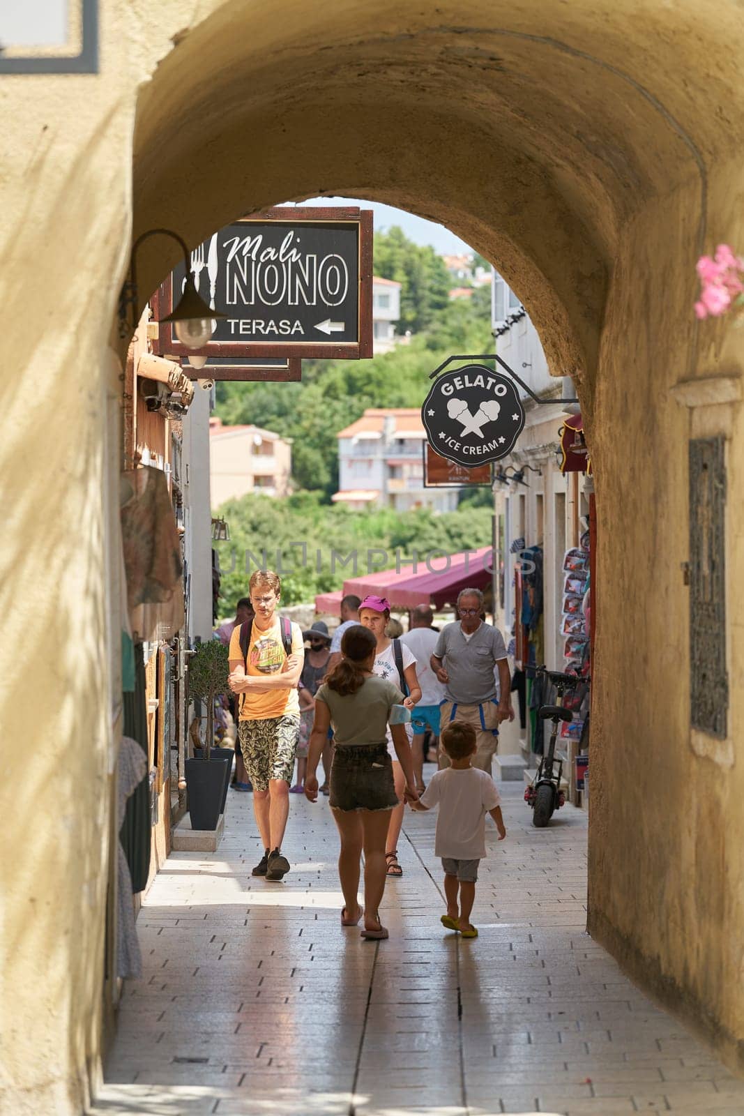 Tourists in an alley with stores in the old town of Krk in Croatia