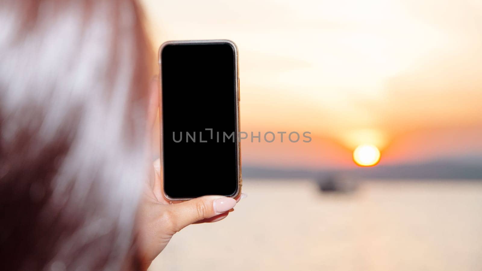 Young woman holding smart phone with mockup black blank display, empty screen for social media app ads at home. Mobile applications technology concept.