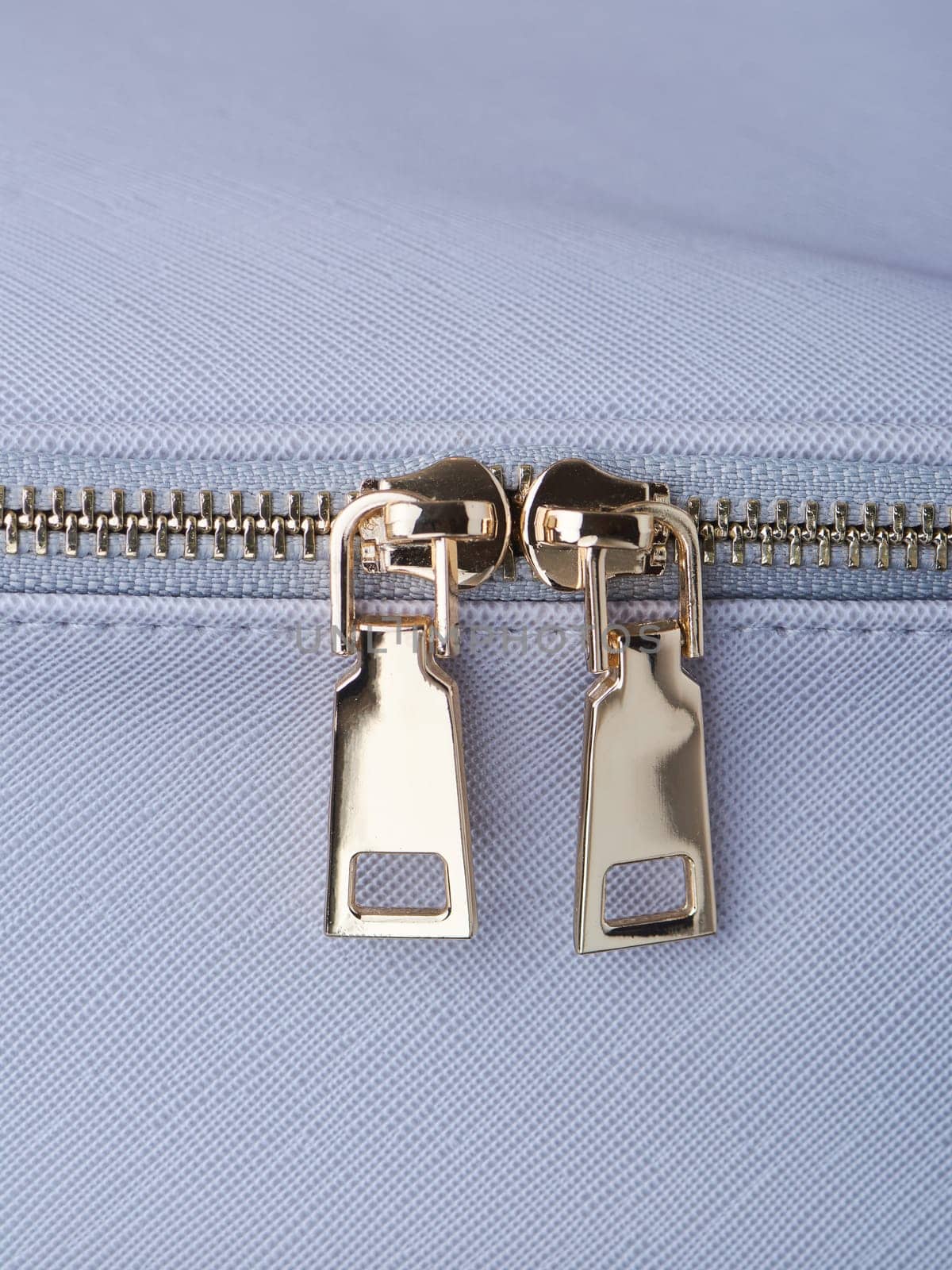 golden zippers with golden zippers are fastened on a blue leather object close-up. High quality photo
