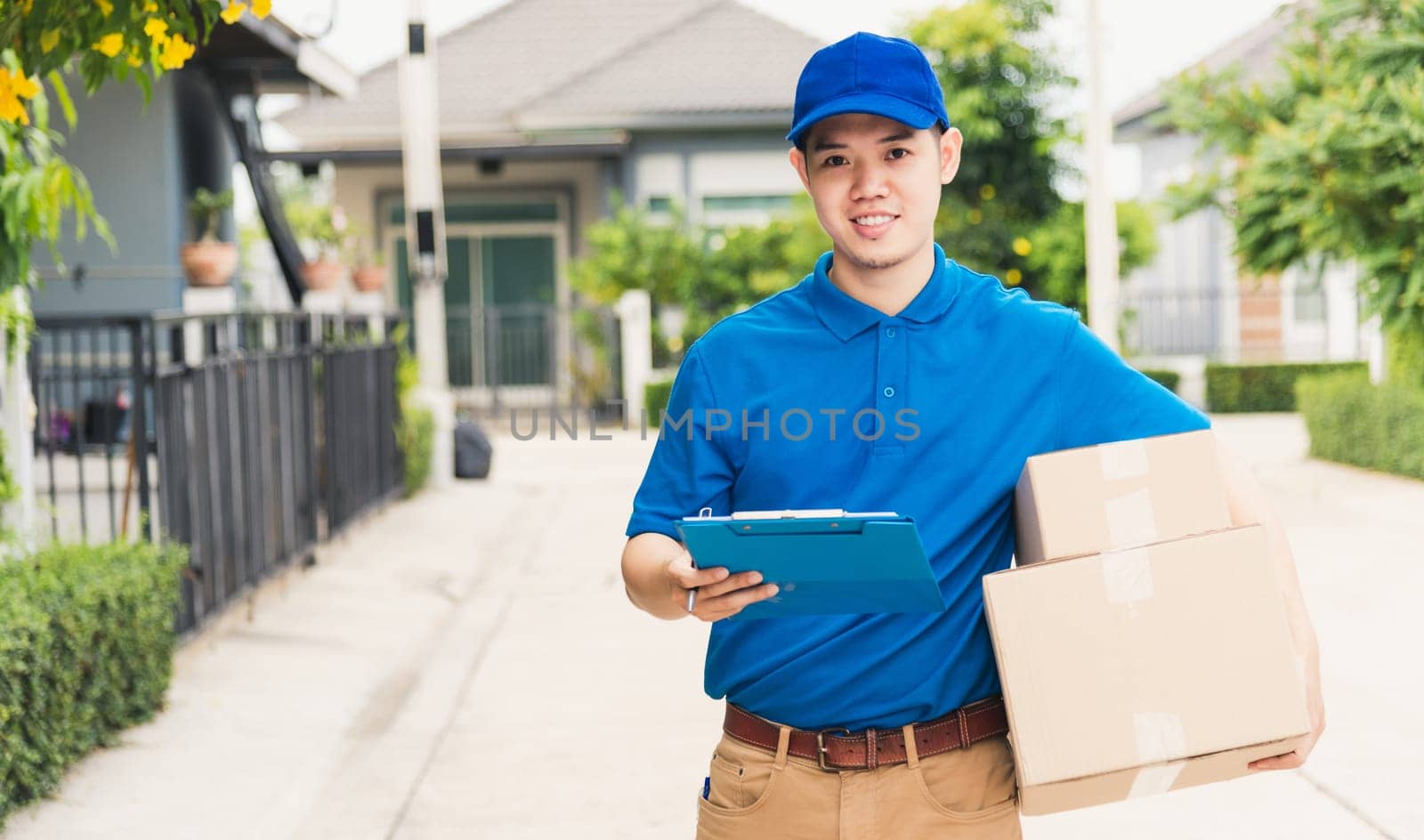 Asian young delivery man courier in uniform hold parcel post boxes service shipment and walking finding and looking for customer home location, Online shopping service concepts