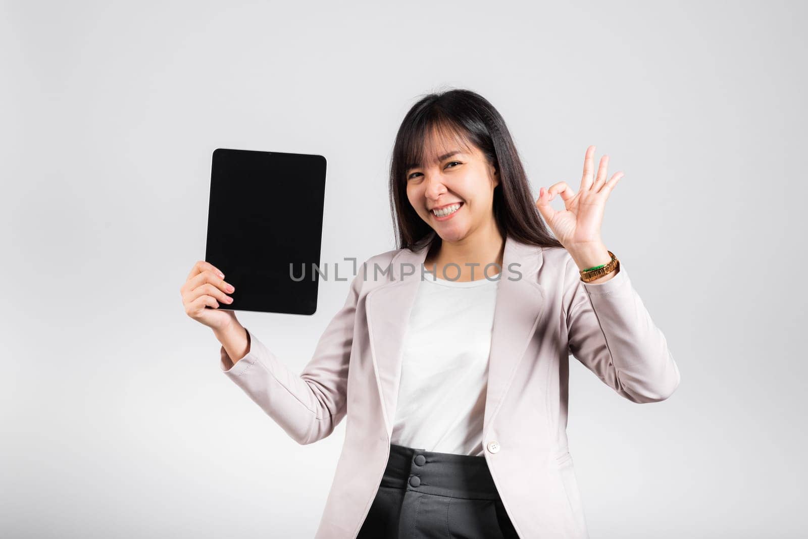 Asian beautiful young woman smiling using tablet computer, Happy female show blank screen digital tablet pc and show OK sing to accept, studio shot isolated on white background