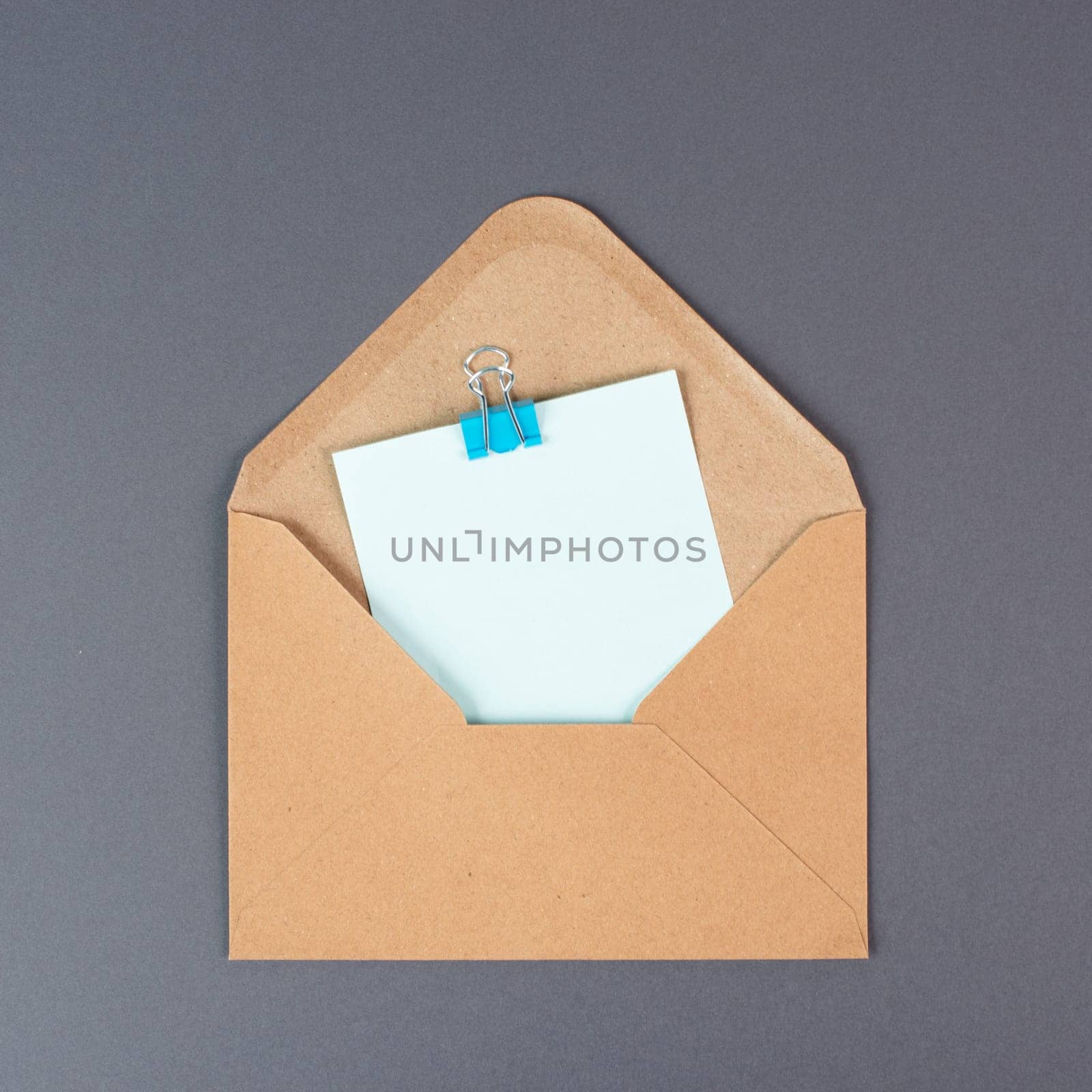 Envelope with an empty paper on a gray colored background, copy space for text, greeting card, communication and announcement concept, reminder