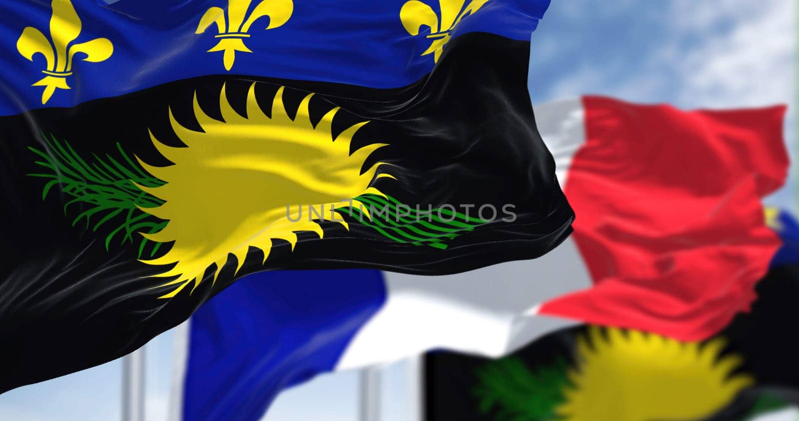 National flags of Guadeloupe waving the with the flag of France on a clear day. Guadeloupe is an archipelago and overseas department and region of France in the Caribbean