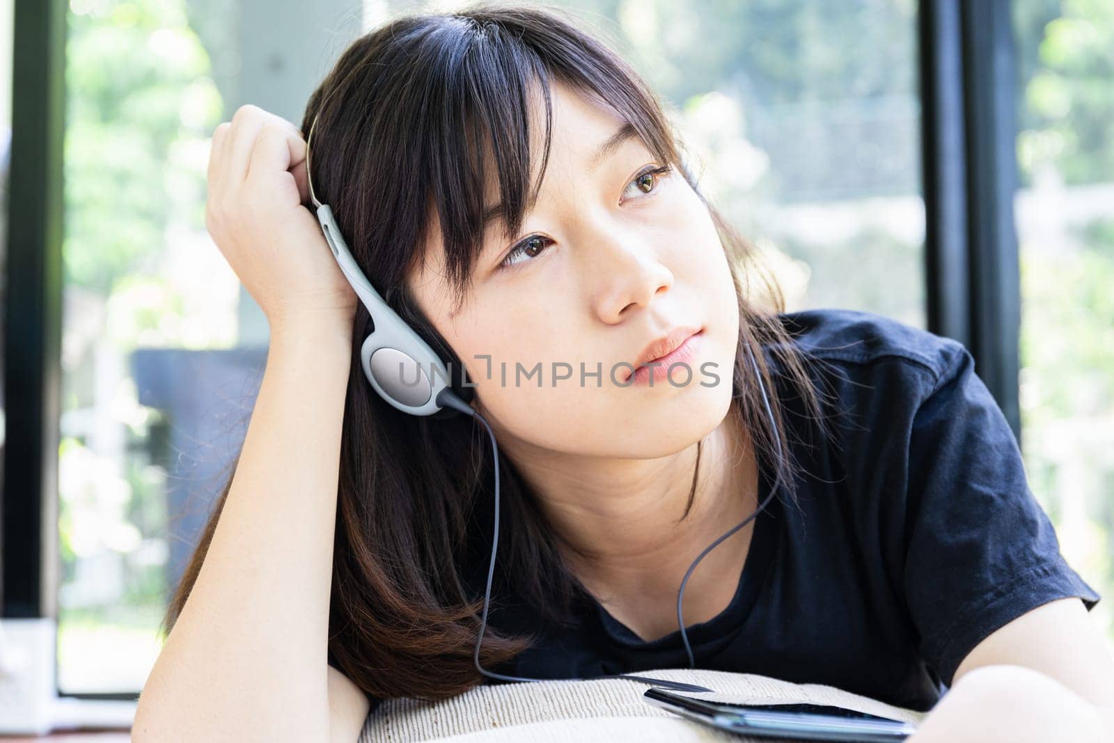 Teenage girl with headphones and listening to music from mobile phone at home