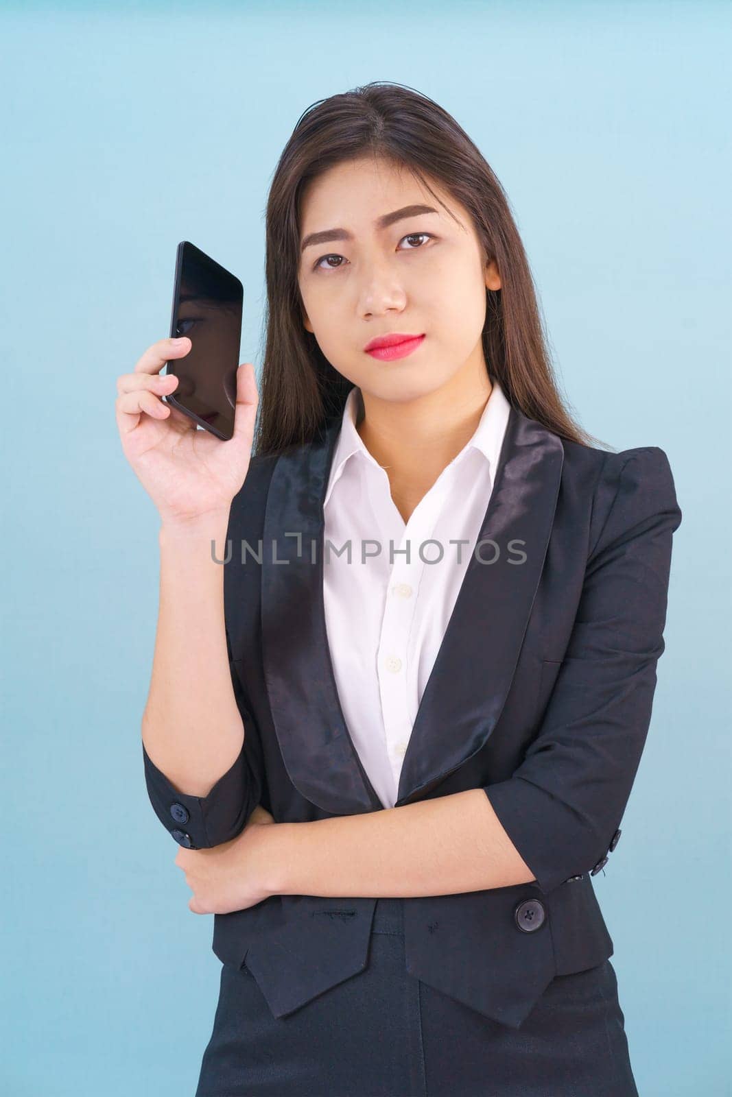 Young women in suit holding her phone standing against blue background