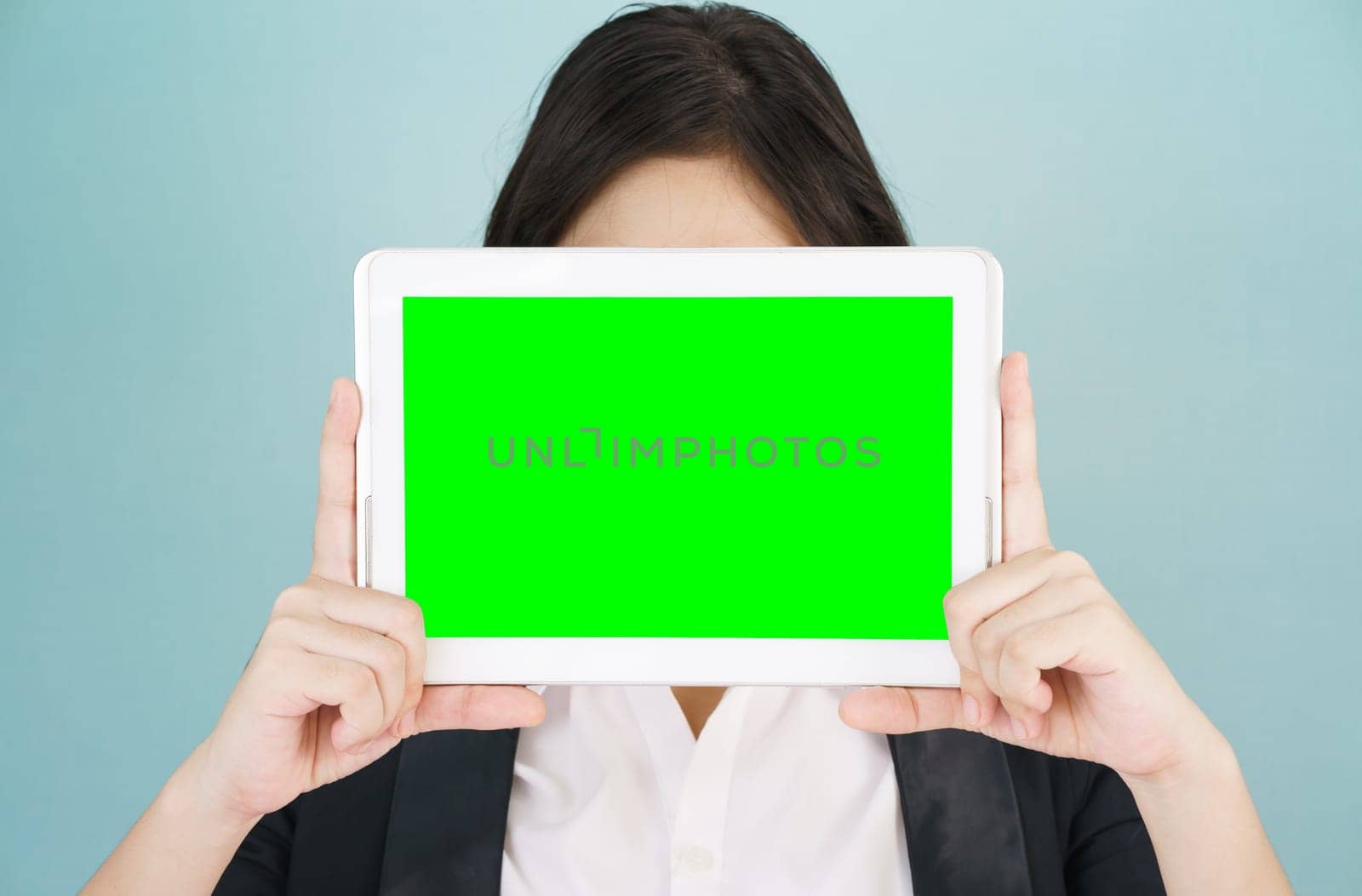 Young asian women in suit holding her digital tablet mock up standing against green background