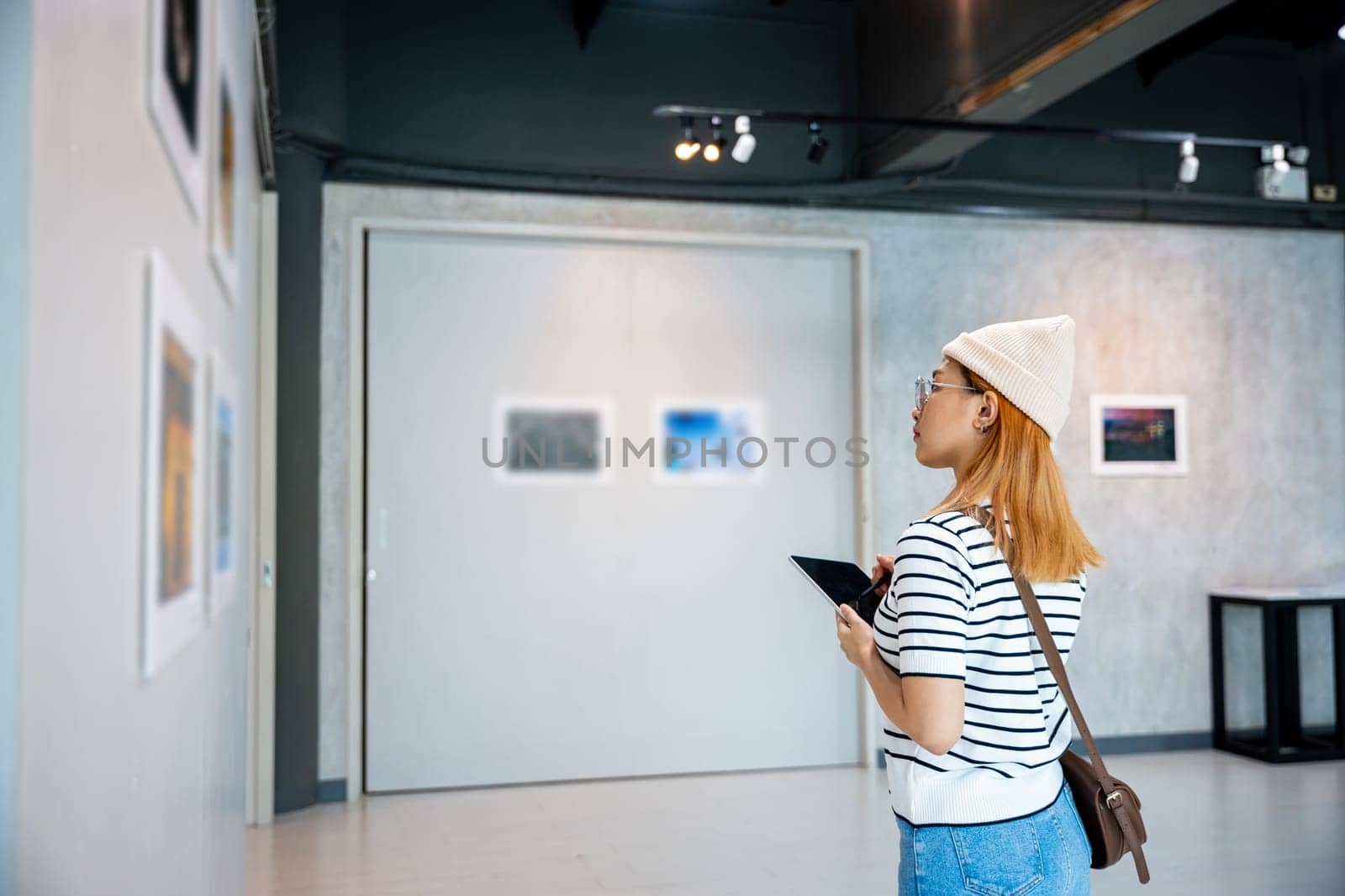 Asian woman note information to tablet at art gallery collection in front framed paintings looking pictures on wall, Young person at photo frame write digital book at show exhibit artwork gallery