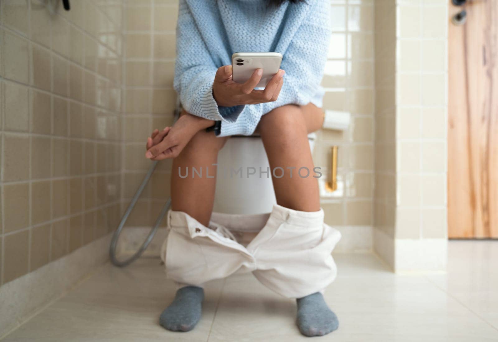 woman using phone while using the bathroom