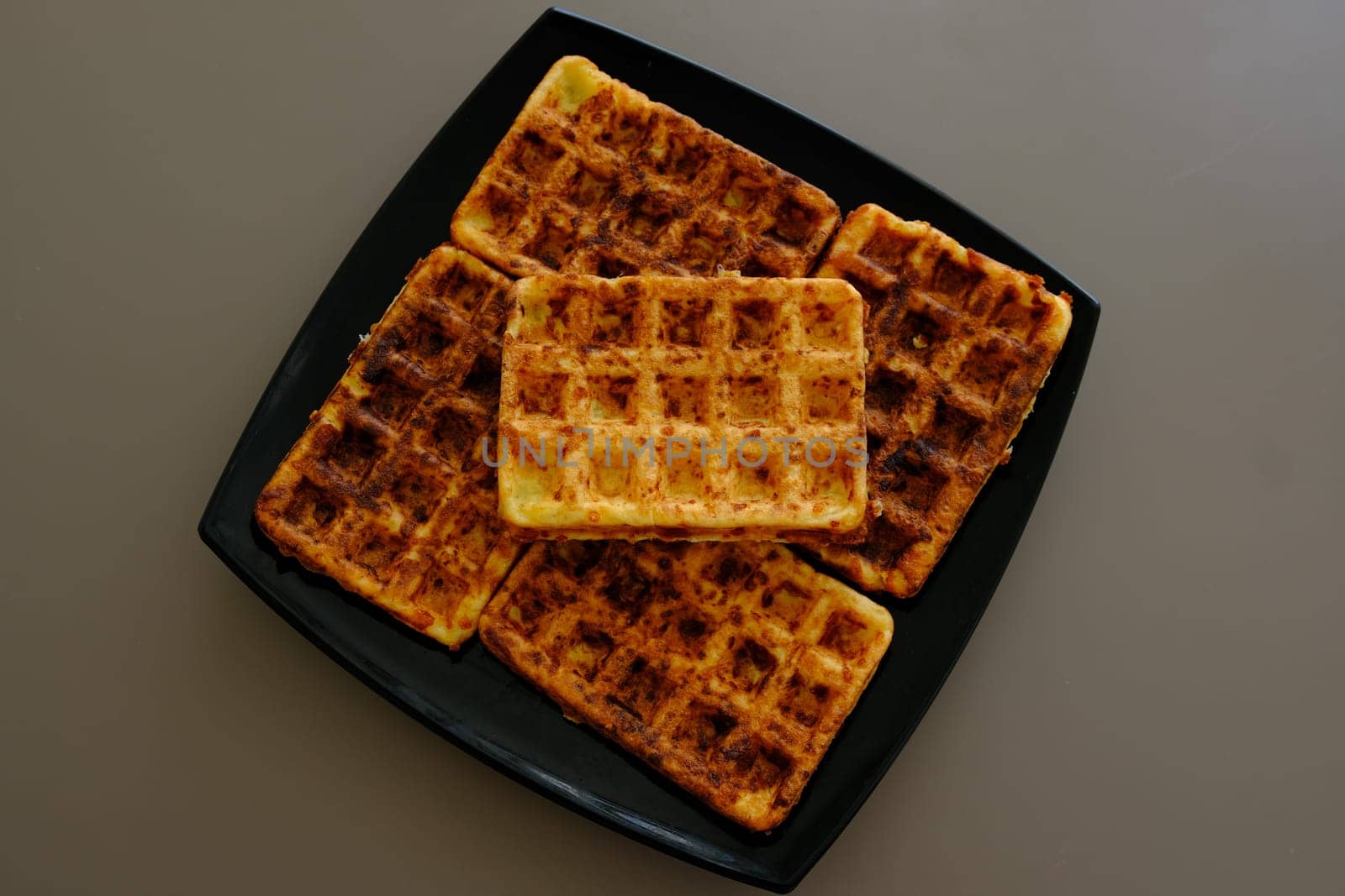 Sweet waffles prepared for serving. A tasty dessert eaten with fruit and preserves. Dark background