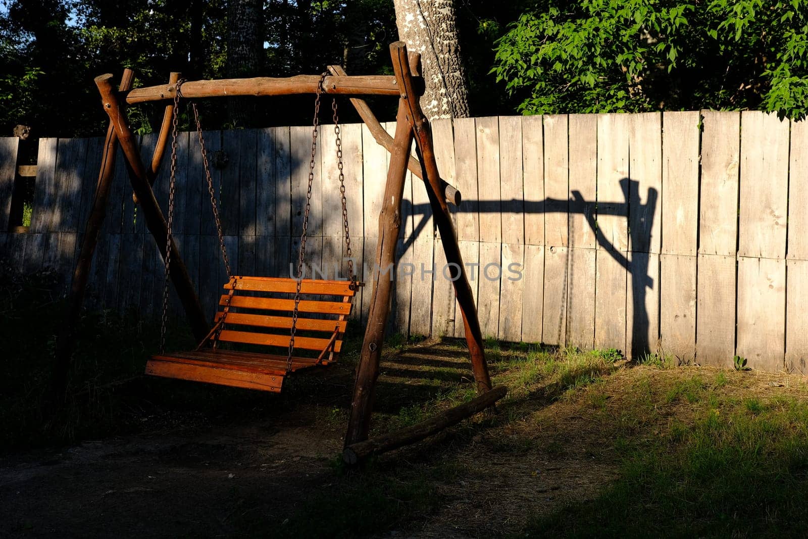 Swing wooden bench in a garden during a sunny day