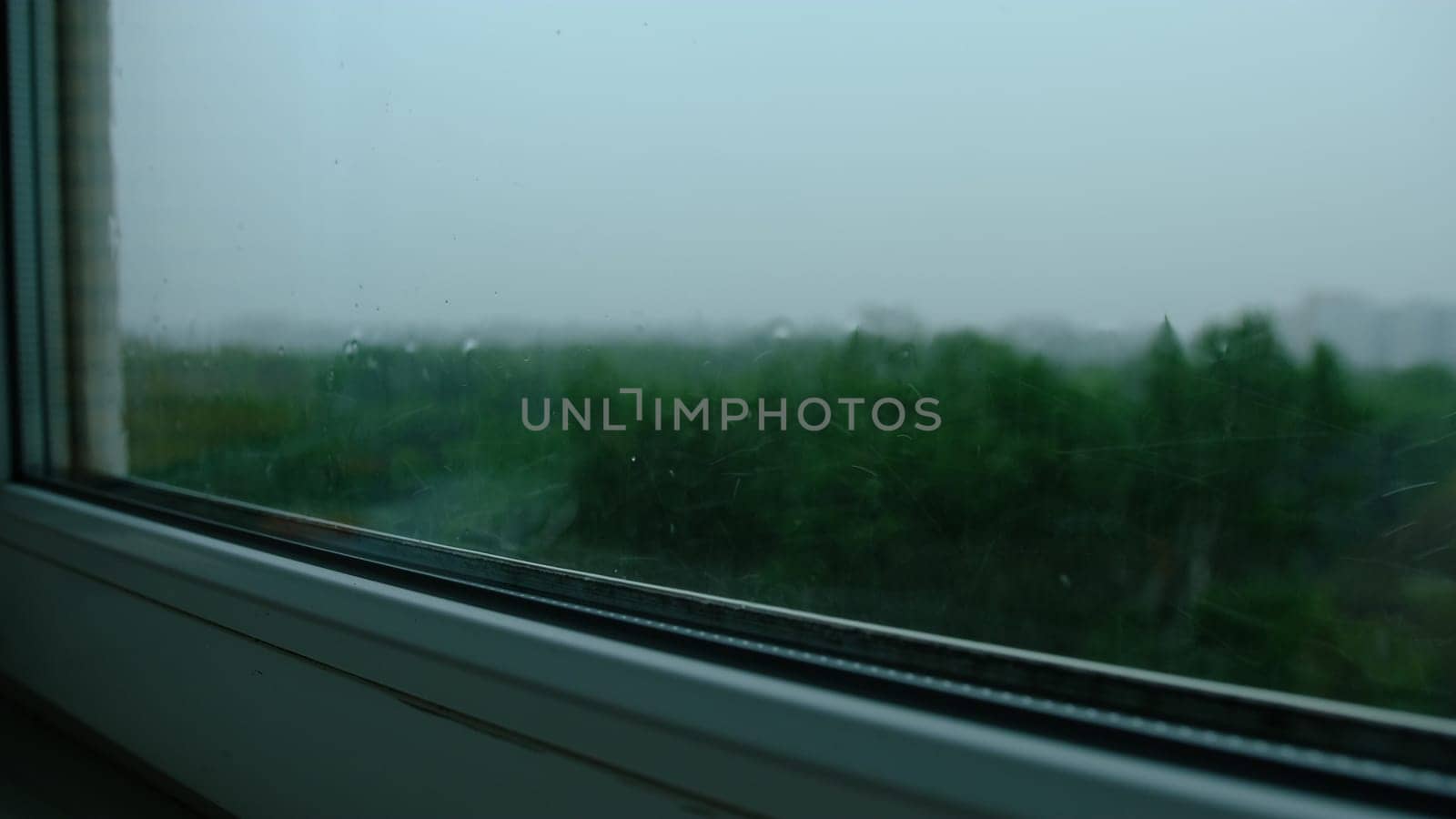 Raindrops on the window pane. Blurred background outside the window in the rain
