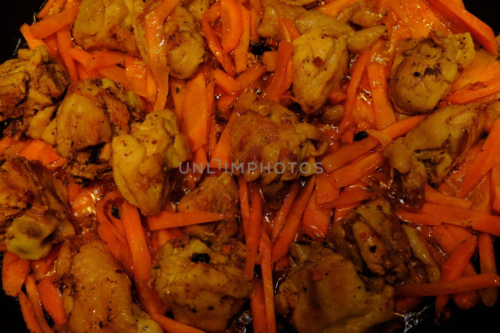 Homemade Korean Spicy chiken dish, frying chiken with carrot in a pan with sunflower oil