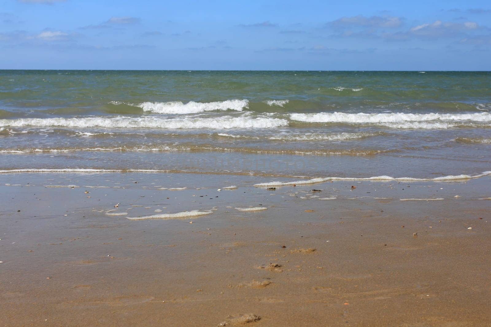 Waves with whitecaps flood the sandy beach.Wellen mit weißen Schaumkronen überfluten den Sandstrand .