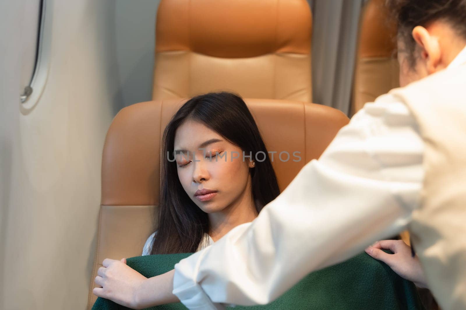 Stewardess taking care of passenger. Flight attendant covering tired sleepy woman with blanket during trip. Flight with comfort concept