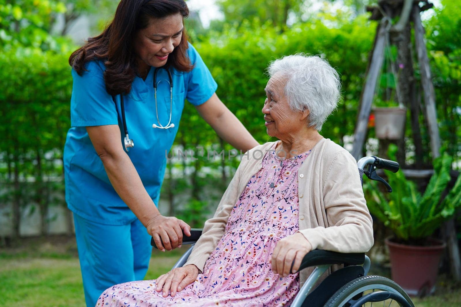 Doctor help Asian elderly woman disability patient sitting on wheelchair in park, medical concept.