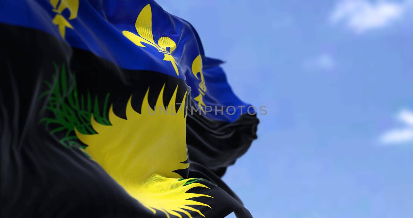 Flag of Guadeloupe waving in the wind on a clear day. Guadeloupe is an archipelago and overseas department and region of France in the Caribbean