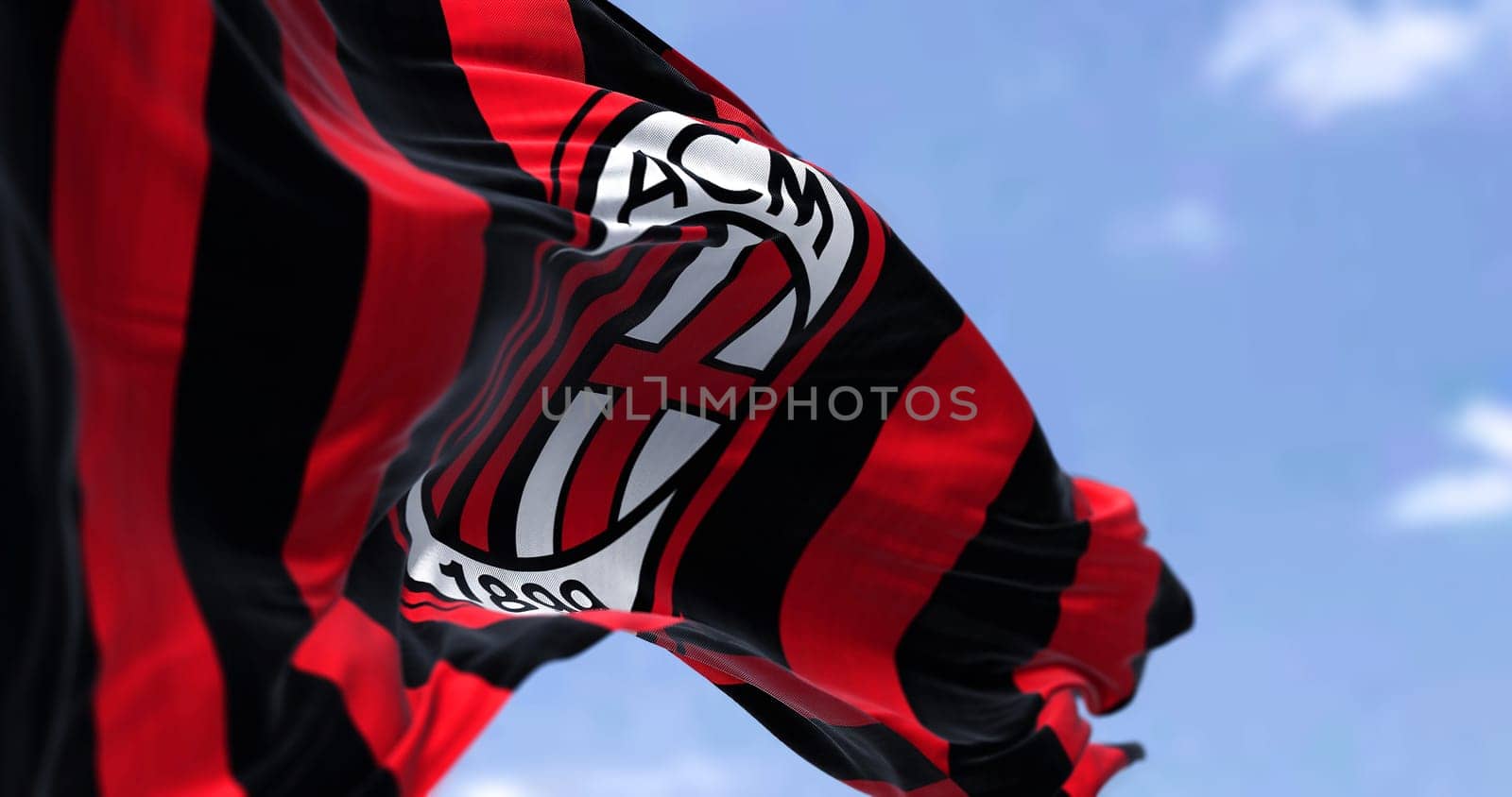 Milan, Italy, July 2022: The flag of A.C. Milan waving in the wind on a clear day. Milan is a professional football club based in Milan, Italy