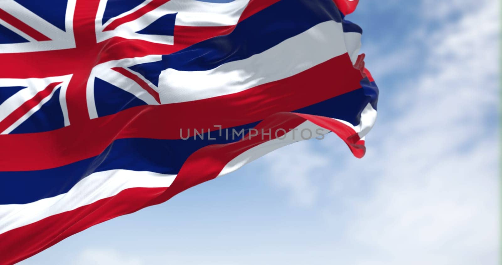 The US state flag of Hawaii waving in the wind on a clear day. Hawaii is a state in the Western United States, located in the Pacific Ocean. Democracy and independence. Seamless loop in slow motion
