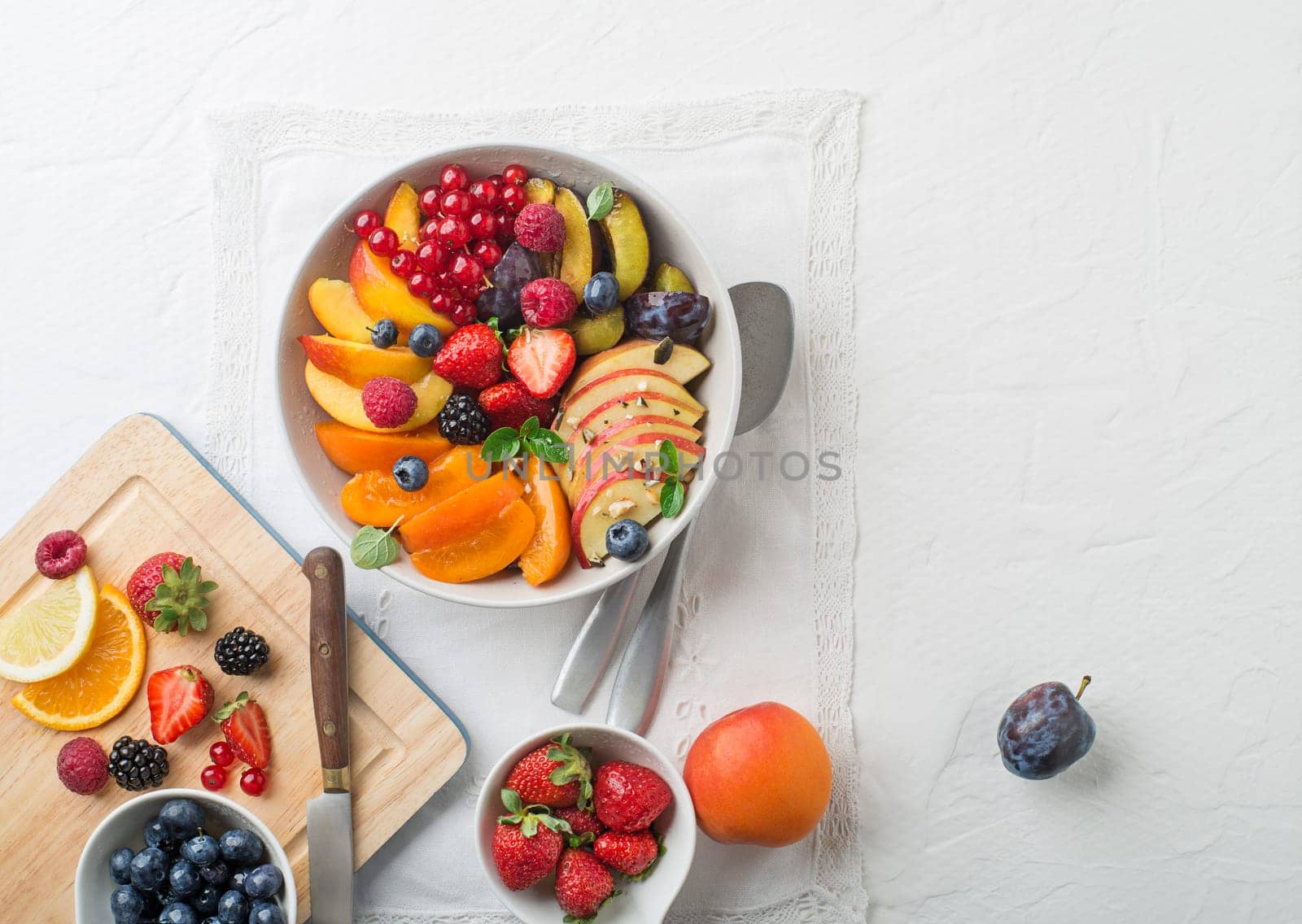 Preparing of healthy fresh fruit salad on white table background