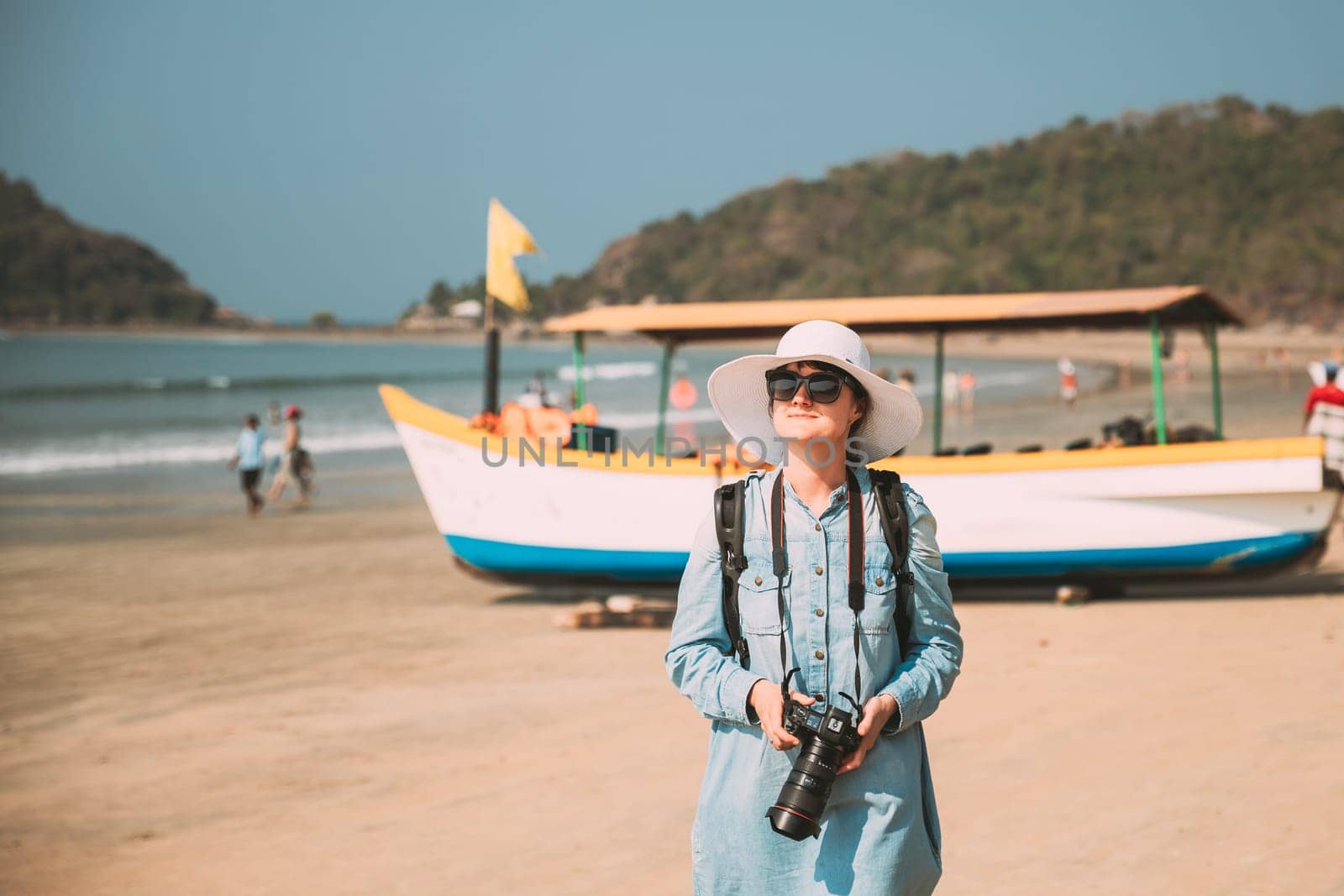 Canacona, Goa, India. Young Caucasian Lady Woman With Camera Standing On Famous Palolem Beach Near Arabian Sea In Summer Sunny Day.