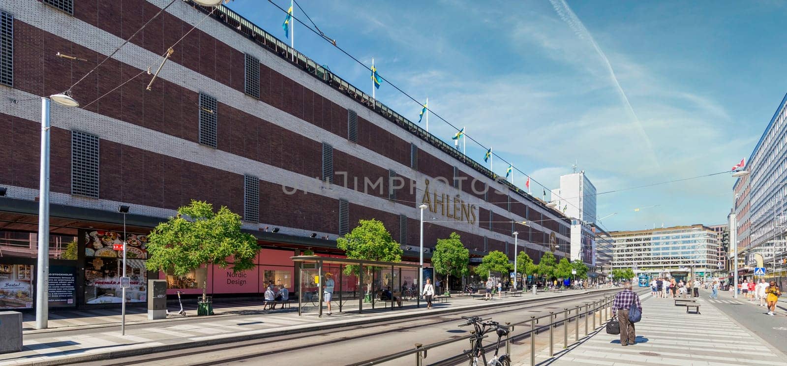 Stockholm, Sweden - June 25 2022: Norrmalm district in central Stockholm, with the famous Swedish department store, Ahlens, few pedestrians, and low traffic, in a sunny summer day