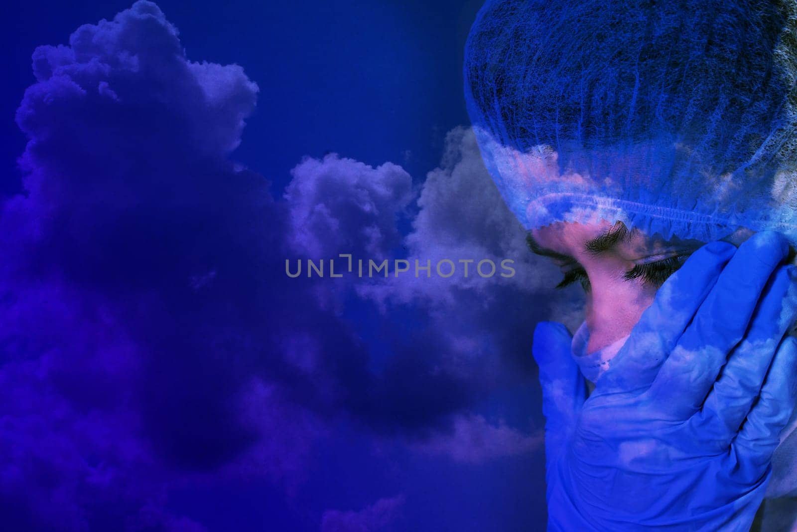 A woman doctor in a medical mask and gloves is crying against the backdrop of storm clouds. Dramatic collage.