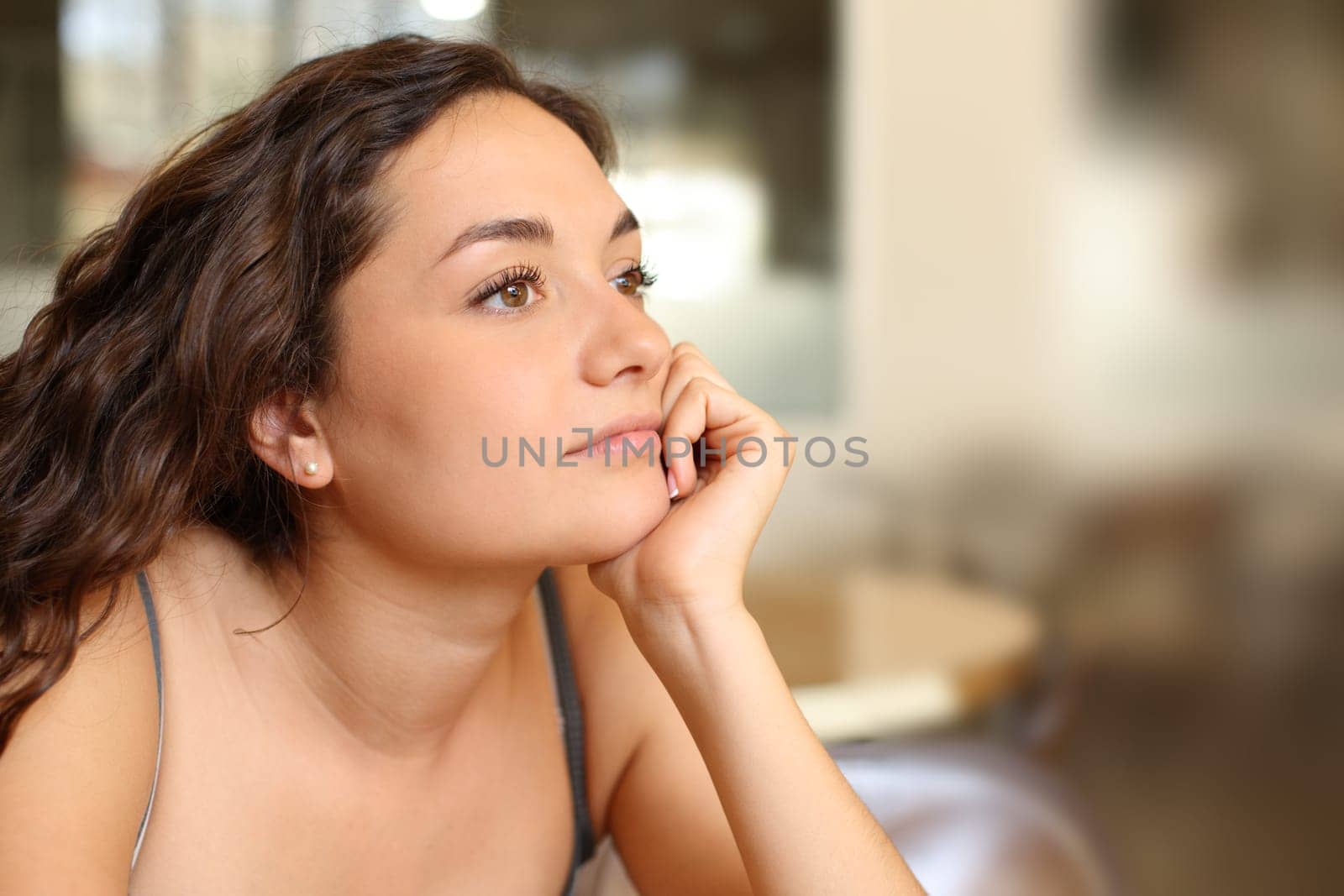 Pensive woman looking away distracted sitting in a coffee shop