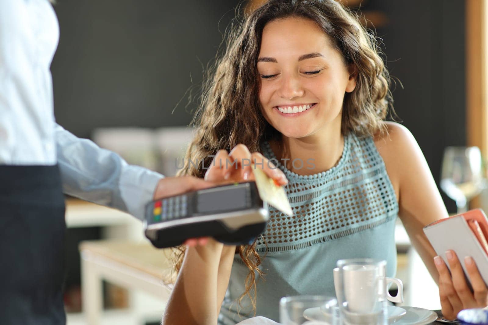 Happy woman paying lunch in a restaurant with credit card