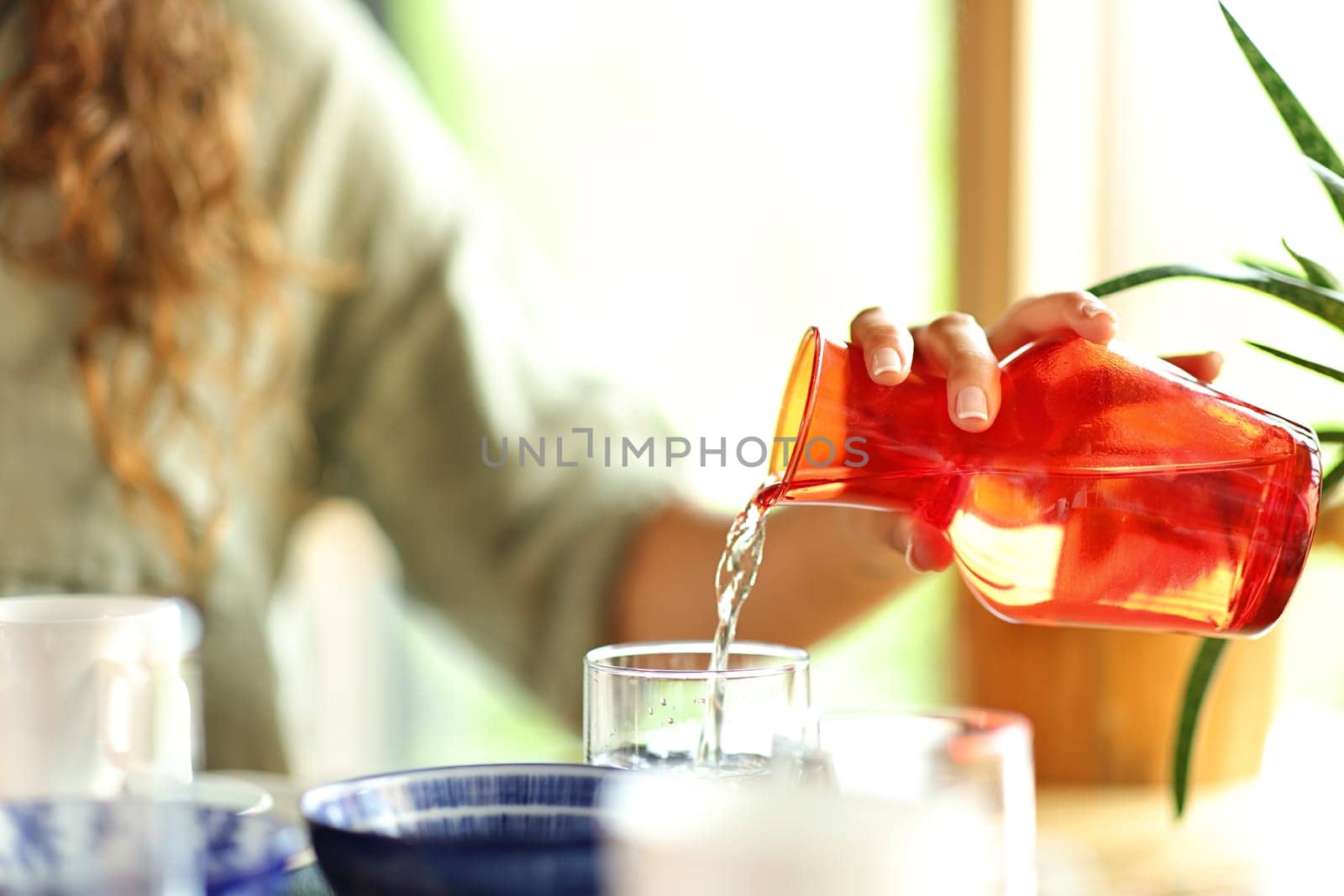 Close up portrait of a woman hand pouring water into a glass in a restaurant