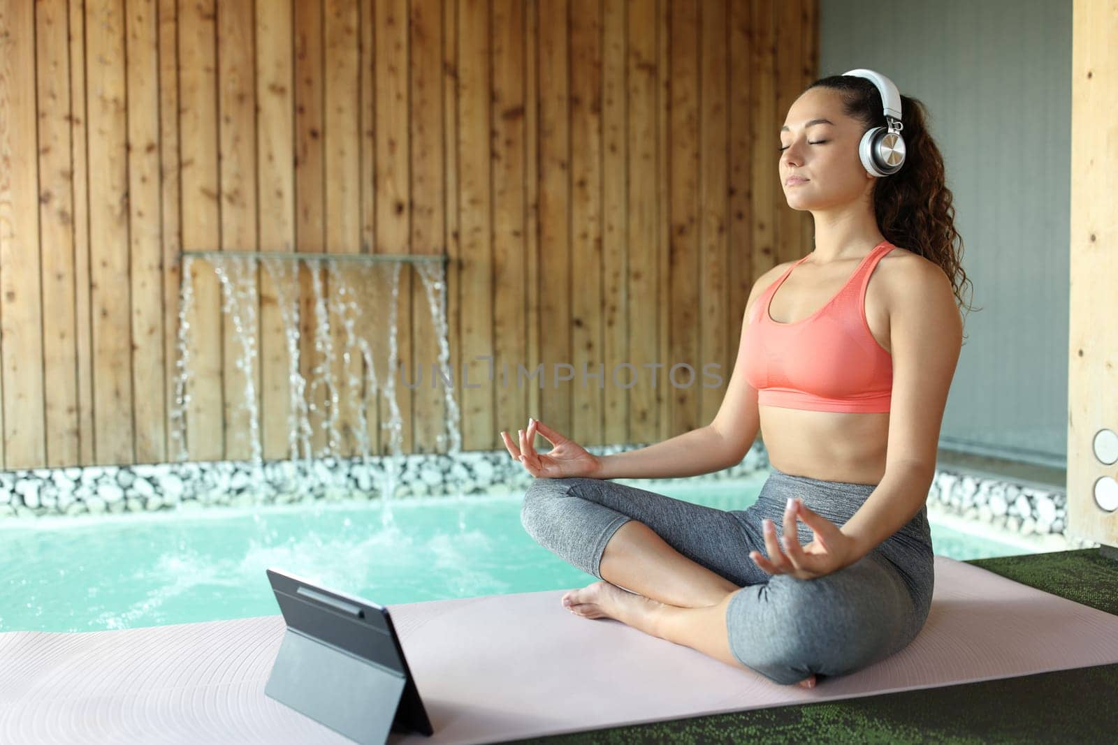 Woman e-learning yoga using laptop and headphones to meditate in a spa