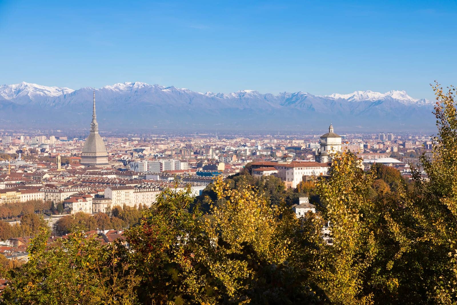 Turin, Italy - Circa November 2021: panorama with Alps and Mole Antonelliana,. Skyline of the symbol of Piedmont Region withi Monte dei Cappuccini - Cappuccini's Hill. Sunrise light, Autumn.