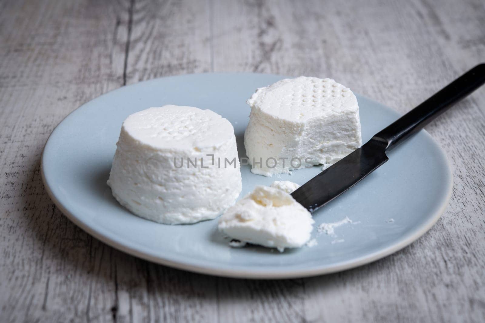 eating a fressh white cheese in a plate on a wooden table