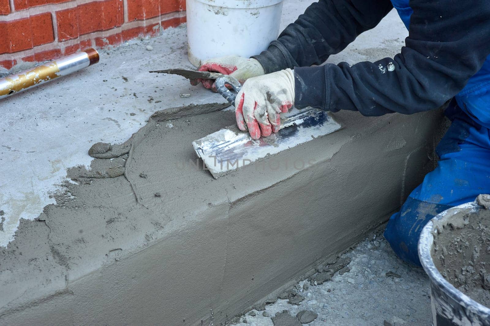 a worker uses a spatula to distribute the cement mixture along the ramp. High quality photo