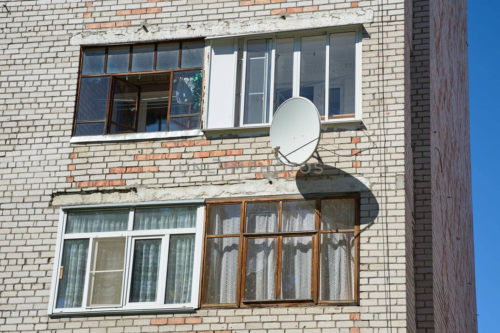 A satellite dish is hanging on the wall of a brick house. High quality photo