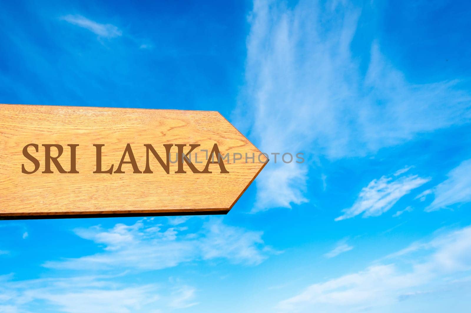 Wooden arrow sign pointing destination SRI LANKA against clear blue sky with copy space available. Travel destination conceptual image