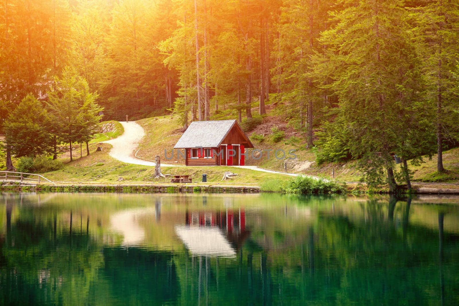 Lake fusine during a beautiful sunset with a small hut reflected in the water