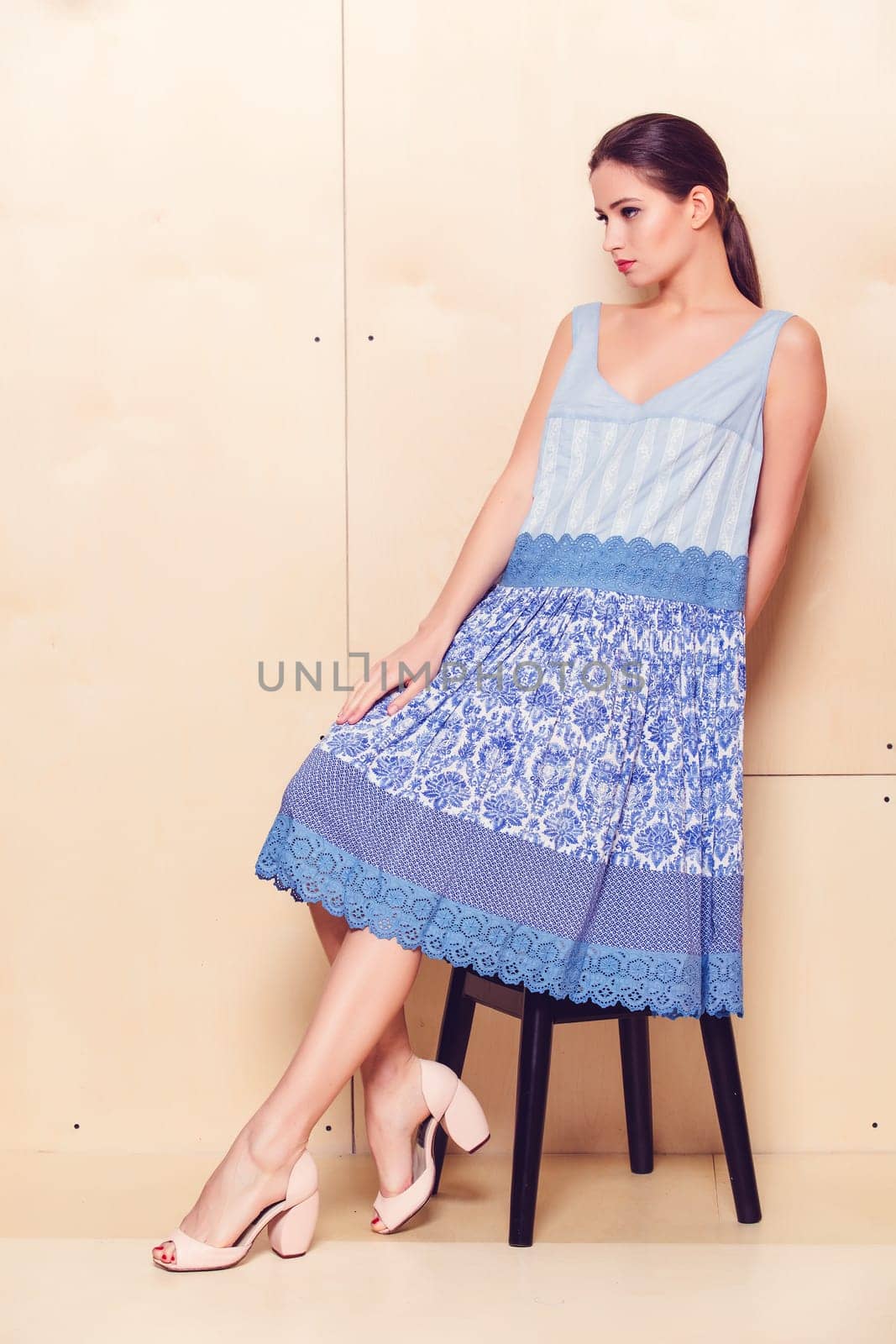 Full body slim woman in blue sundress on wooden background