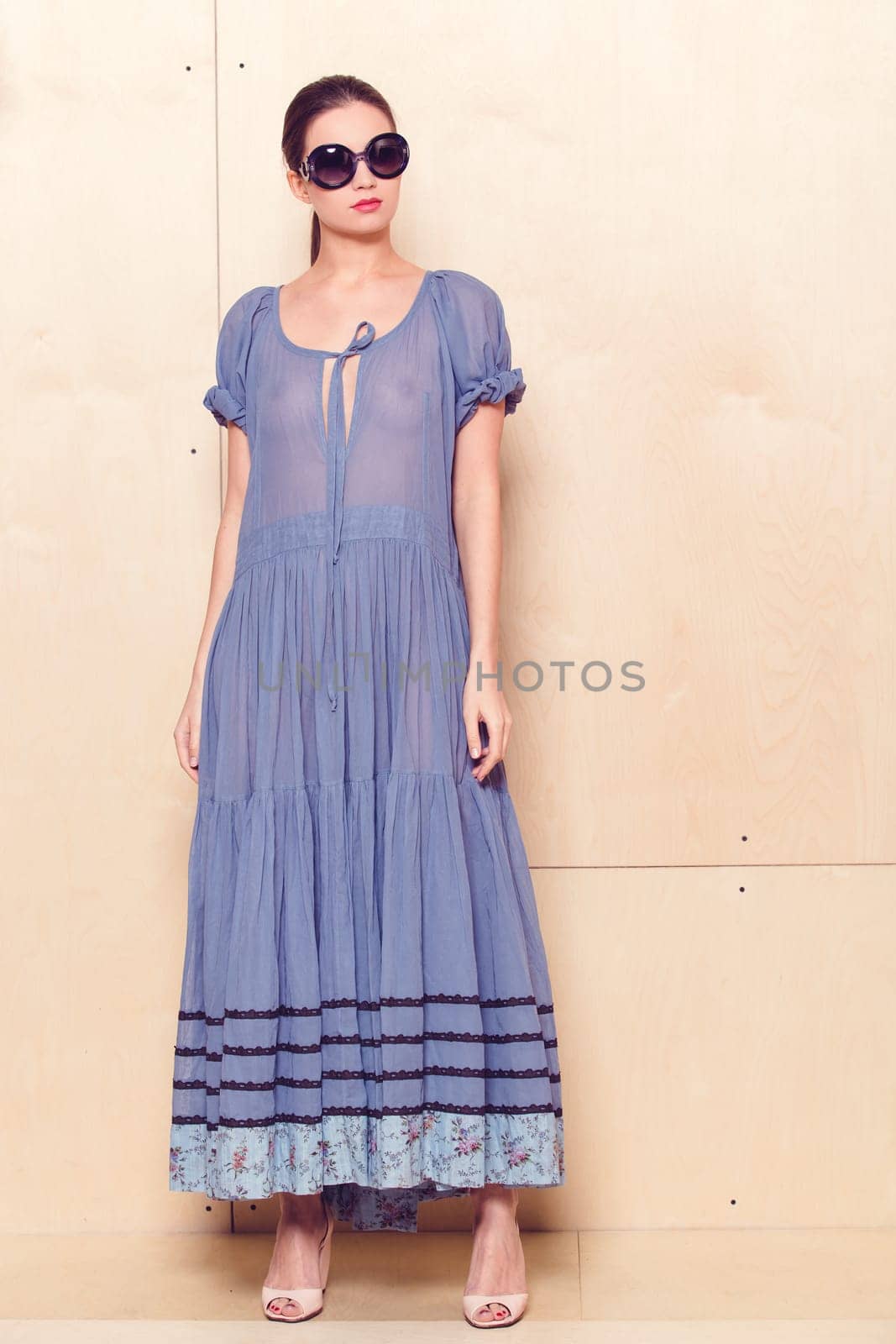 Full body slim woman in blue sundress on wooden background