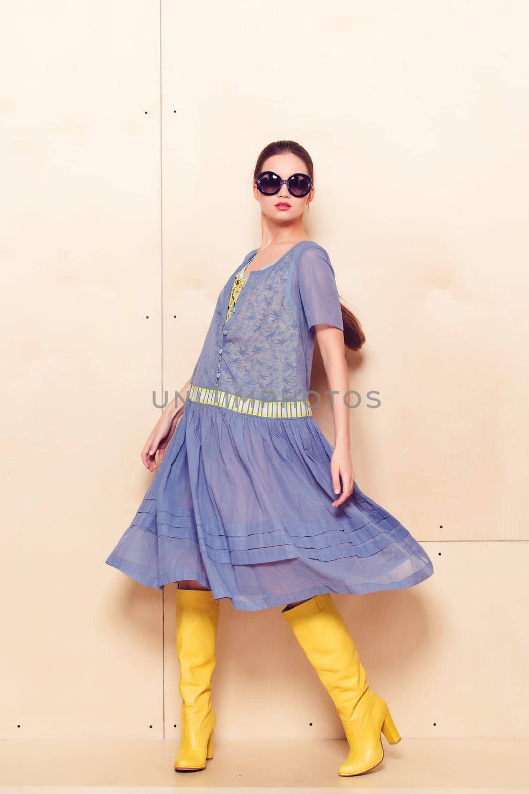 Full body slim woman in blue sundress on wooden background