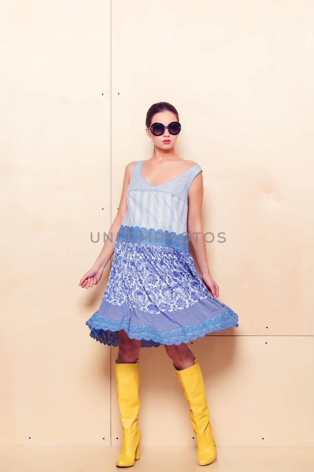 Full body slim woman in blue sundress on wooden background