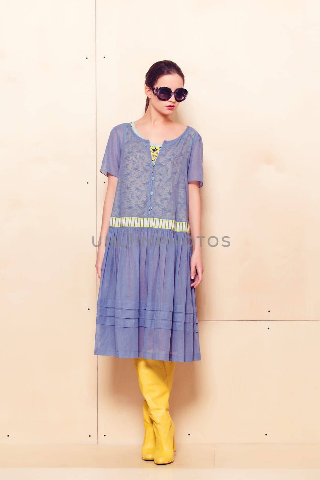 Full body slim woman in blue sundress on wooden background