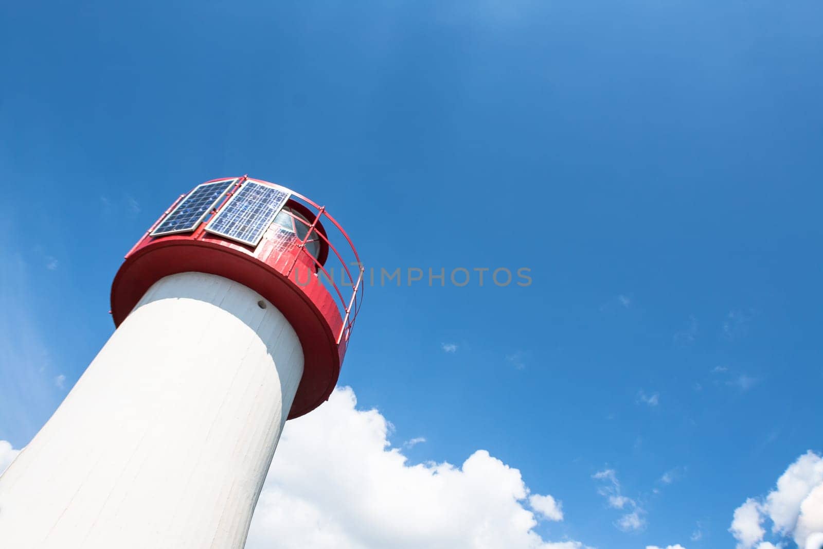Lighthouse Photovoltaic Sky . Sea Mark at the harbor with blue sky with clouds in background