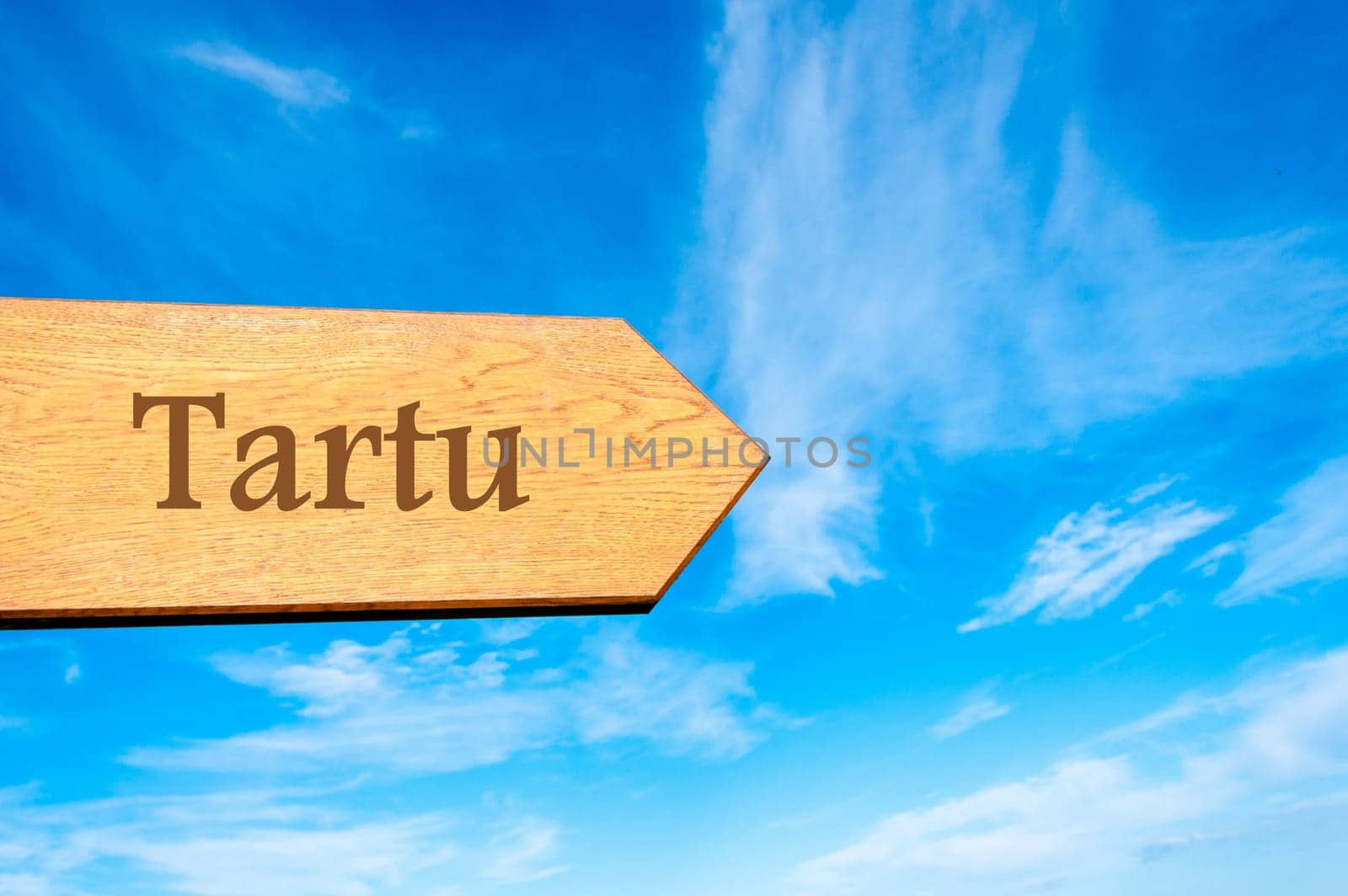 Wooden arrow sign pointing destination TALLINN, ESTONIA against clear blue sky with copy space available. Travel destination conceptual image