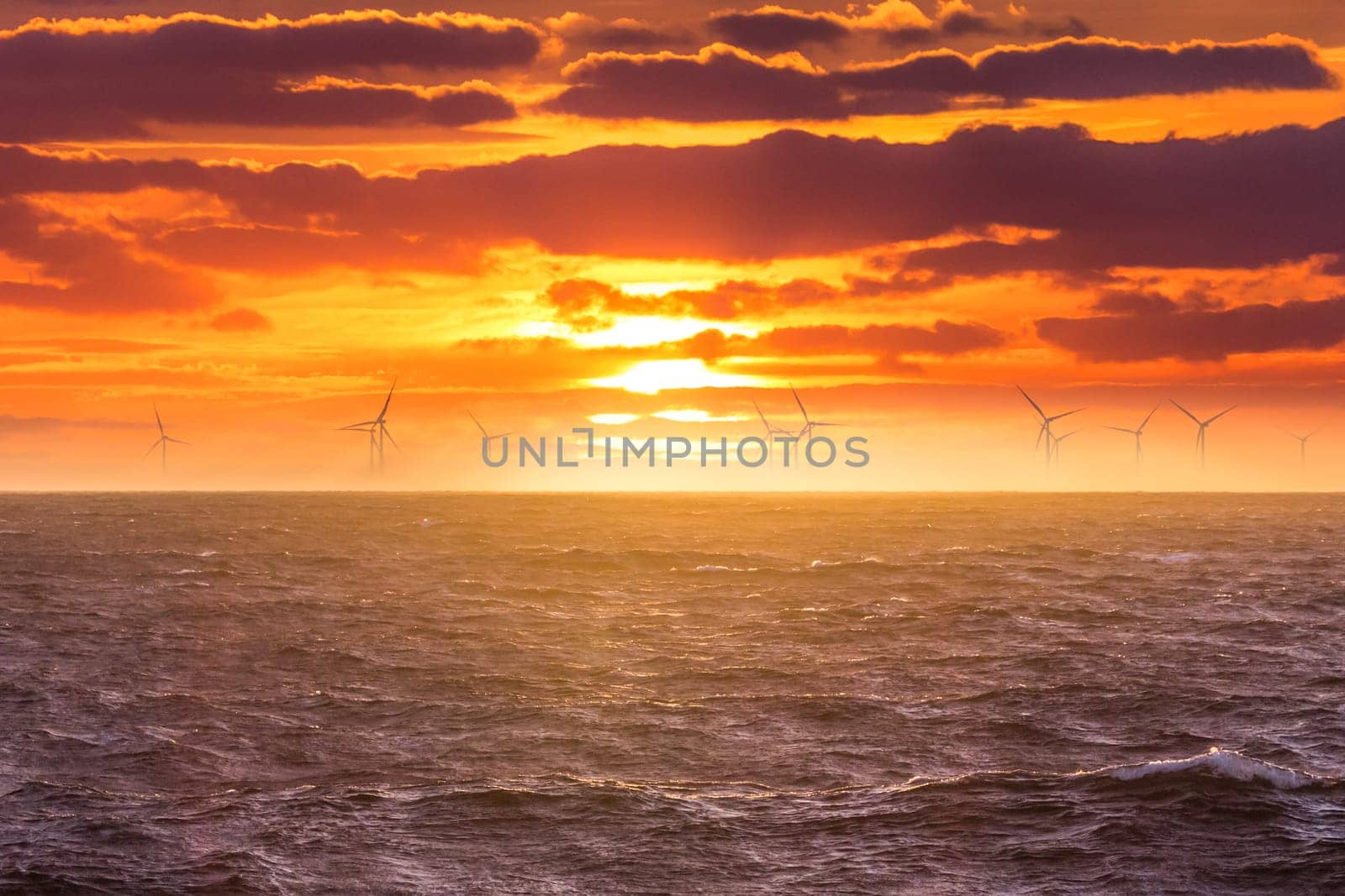 Sunrise at decarbonization industry windmills business for regenerative energies. Clean energy renewables preventing climate change.