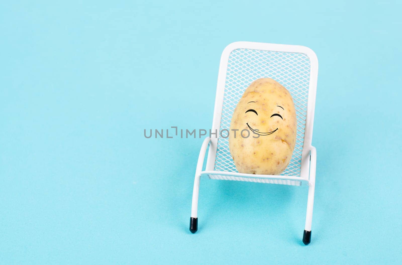 Potato with a funny face is sitting in lounge chairs, happy holiday, greeting card