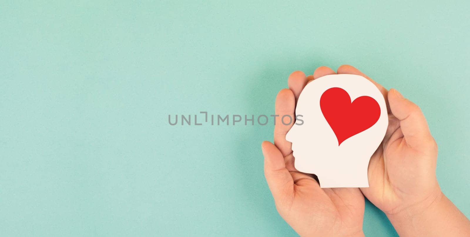 Holding a head with a red heart in the hands, symbol of love and positive emotion, charity and support