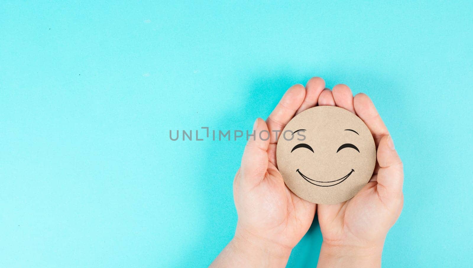 Holding a smiling face in the hands, mental health concept, positive mindset, support and evaluation symbol
