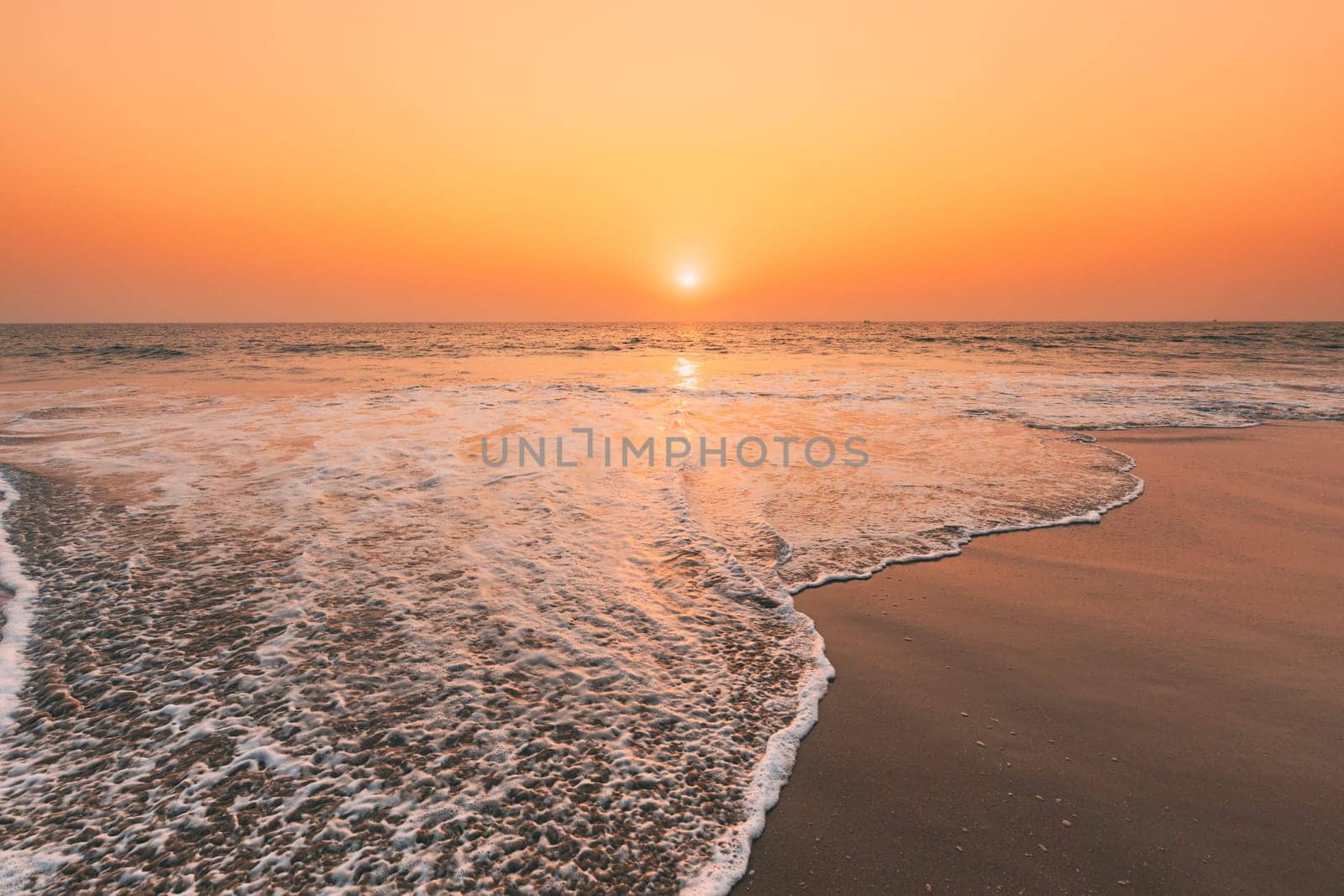 Sunset Sun Above Sea. Natural Sunrise Sky Warm Colors Over Ripple Sea. Ocean Water Foam Washing Sandy Beach At Sunset.