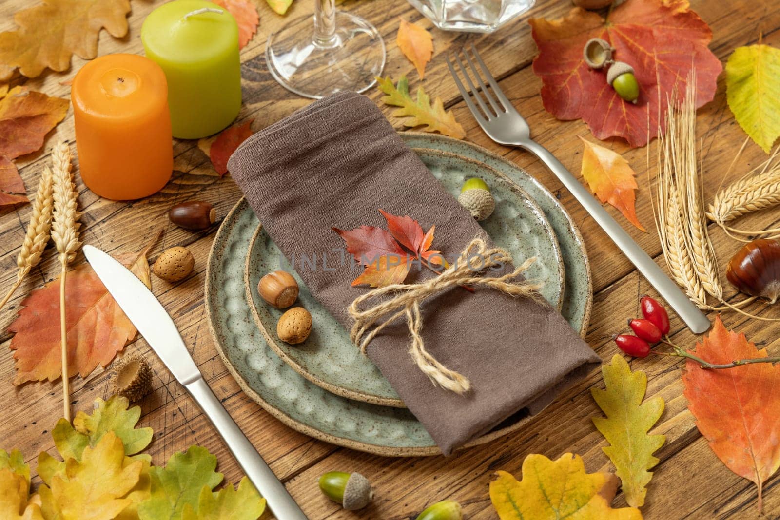 Autumn rustic table setting between leaves and berries on vintage wooden table close up. Thanksgiving, halloween or harvest concept